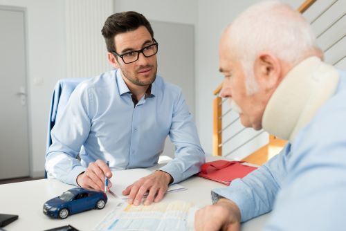 Older man in neck brace meeting with personal injury lawyer