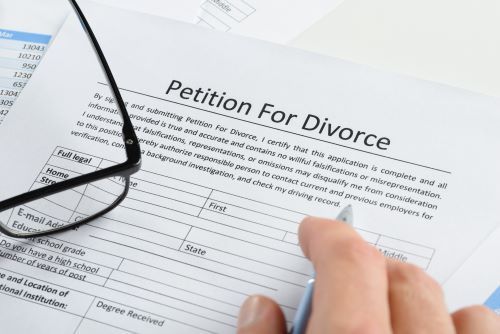 Petition to file for divorce form with hand with pen.