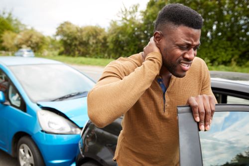 African American man holding neck with personal injury after car rear-ended.