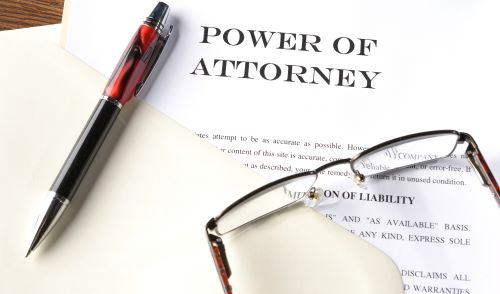 Power of Attorney legal document with pen and reading glasses.
