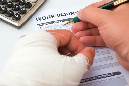 Man with injured and wrapped hand filling out "Work Injury" form.